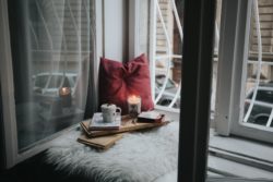 Polster, Kerzenlicht, Bücher, Tasse Kaffee auf Fensterbank